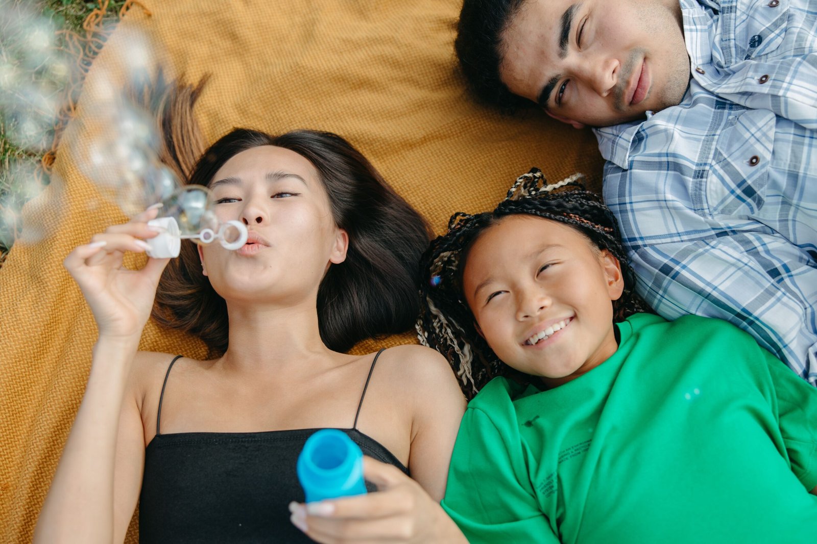 A family lying on a blanket and blowing bubbles