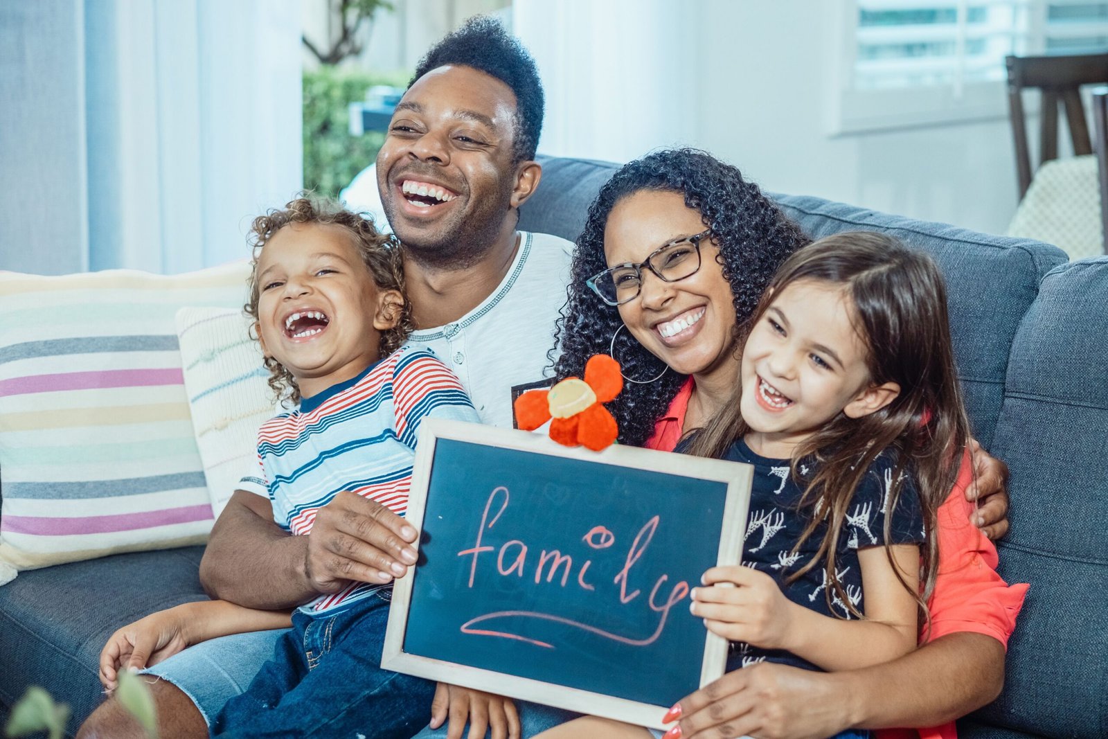 A family on the sofa holding a sign that says family